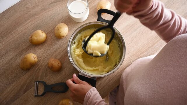 Preparing mashed potatoes by mashing boiled potatoes. Top view