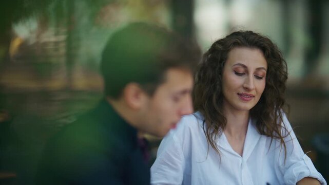 Two business professionals engage in a focused outdoor meeting. They share ideas and converse in a relaxed setting.