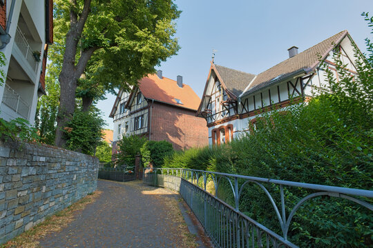 A sunny pathway winds between historic half-timbered buildings and lush greenery in a picturesque European town, ideal for travel content - Soest, Westphalia, Germany