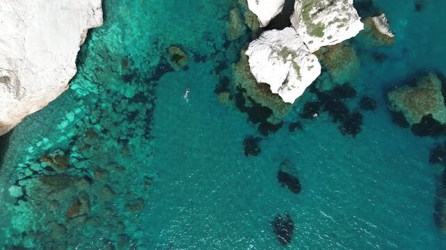 Top down drone shot of turquoise water around Aphrodite Rock sea stack, Cyprus