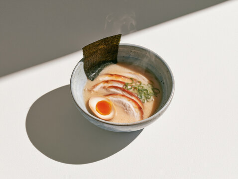 Tonkotsu ramen bowl with chashu pork nori and soft egg in sunlight
