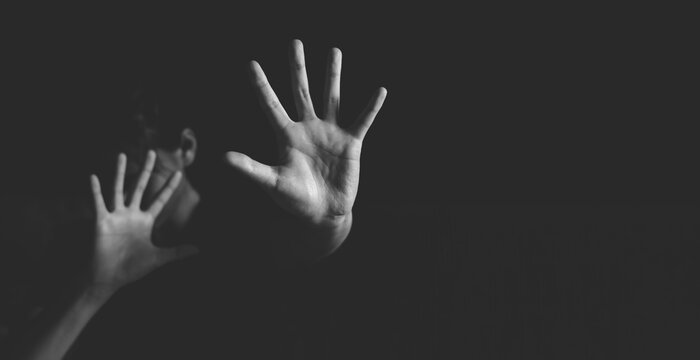 Woman raising an open palm to reject abuse and exploitation, symbolizing safety, freedom, justice, human rights, victim support, and human trafficking awareness.