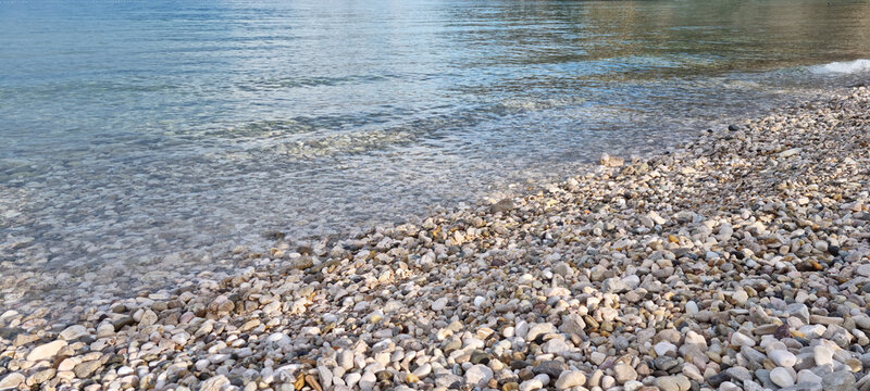 A beautiful pebble beach with crystal clear turquoise sea water splashing gently on the shore in Baska on Krk island.