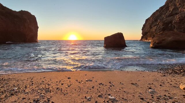 Sunset beach ocean golden light tranquil waves washing on a sandy shore between rugged rocks at dusk a peaceful natural landscape