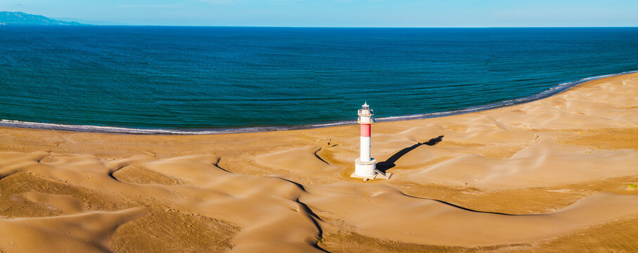 Fangar Lighthouse on sandy Mediterranean coastline with rolling dunes in the Ebro Delta aerial view