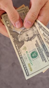 Vertical video. United States Dollar Banknotes Magically Disappearing One by One From Both Hands Until Nothing Remains, Top Down View, Financial Loss, Vanishing Wealth