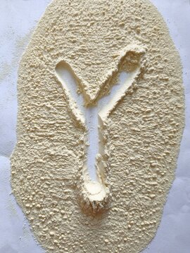 The capital letter Y formed by the absence of light beige powder spread across a clean white background, viewed from directly above
