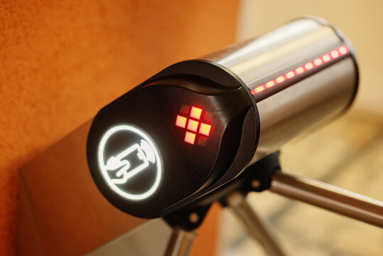 Indoor modern turnstile reader with illuminated contactless payment symbol and red LED X stop signal. Security entry control system for public or private venues.