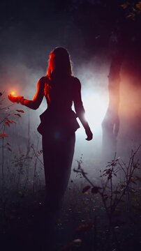 fantasy woman walking in dark dusk night misty forest full fog, Mystical sexy girl back rear view, hand holding glowing ball red orange light magic fire flower. Gothic Lady black long dress. art vedeo