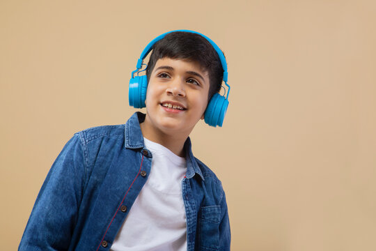 Boy with headphone while listing to music over color background