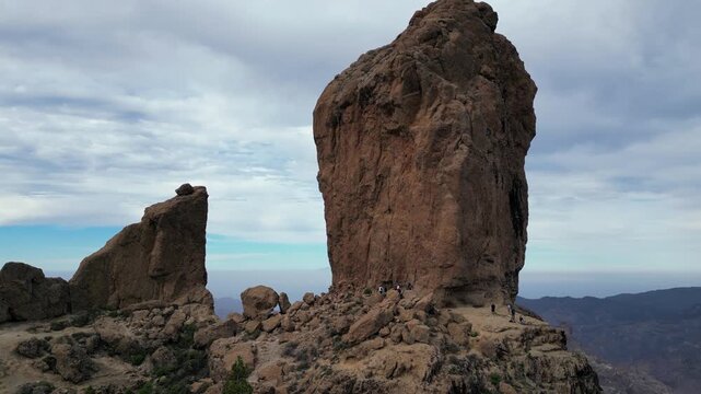 Tourists enjoy a panoramic landscape from the base of the RoqueNublo monolith in Tejeda, GranCanaria, captured in a breathtaking aerial view