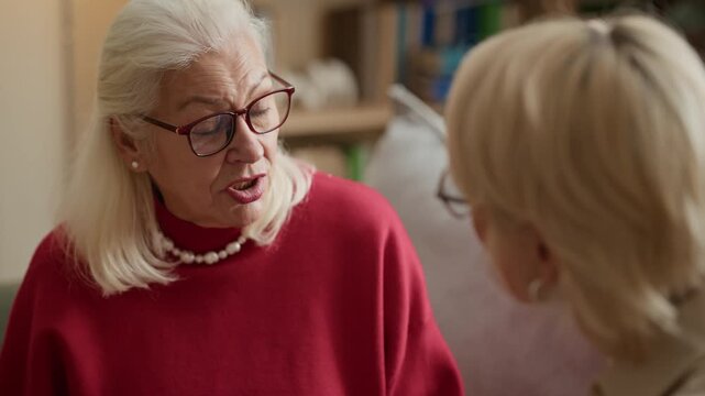 Senior Caucasian woman holding hands with adult daughter and, talking together. Footage is ideal for senior care services or intergenerational relations