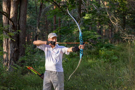 Senior man practicing recurve archery in forest during outdoor training