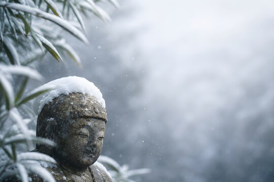 Stone Jizo statue wearing a cap of fresh snow with frosted bamboo in serene winter background