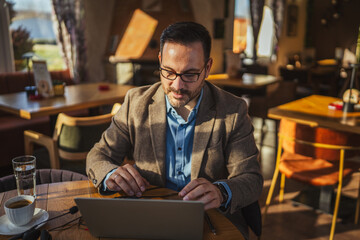 Obraz premium Man working remotely at cafe using laptop