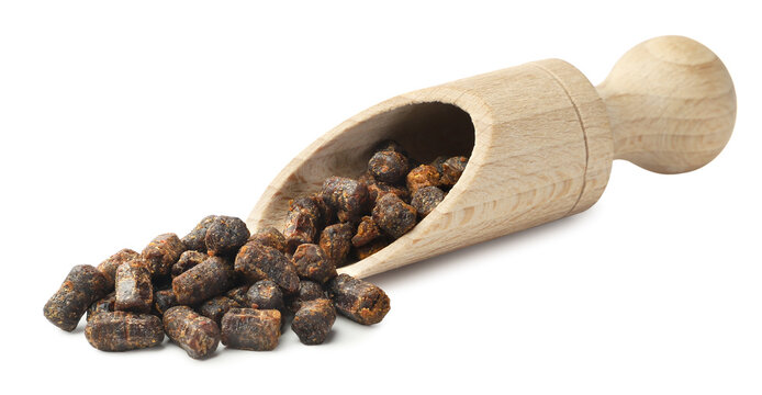 Bee bread spilling from a wooden spatula on a white background. Isolated