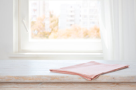 Checkered kitchen towel on wooden table top with white window sill background