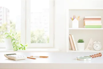 Stylish workplace white table top with stationery, calculator and magnifier on blurred window sill background © didecs