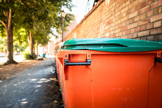 Shallow focus of a typical commercial waste bin located outside a restaurant business in the city of Ely, UK. The footpath leads to the famous Cathedral on the far left.