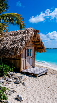 A thatched-roof hut with a wooden deck overlooking a clear blue ocean
