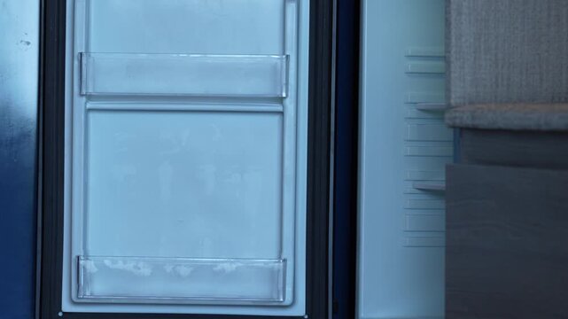 Young girl organizing bottled water neatly inside a mini refrigerator in a hotel room, highlighting responsibility, organization, healthy hydration, and family vacation lifestyle.