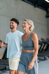 Fototapeta premium Joyful mature woman and partner walking in gym for fitness poster background and wellness lifestyle design