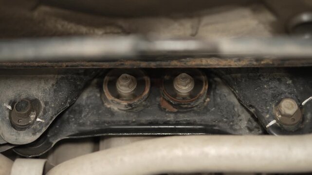 A close-up view of rubber bushings and mounting bolts on a car subframe.