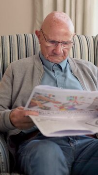 Newspaper, reading and glasses with old man on sofa for obituary check, headlines and relax. Retirement, press release notice and article publication with senior person and tabloid in home for column