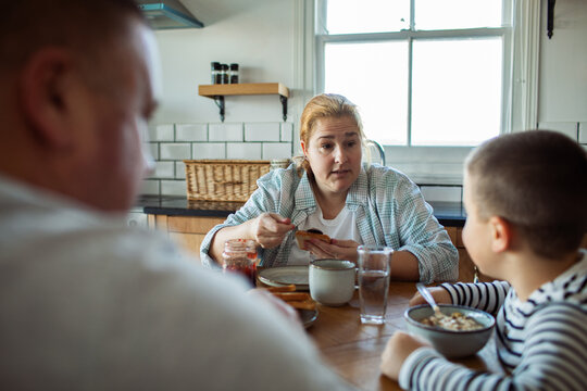 Mother talking with son over breakfast in home kitchen