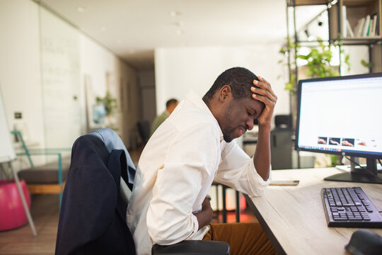 Stressed office worker with headache and stomach pain at desk