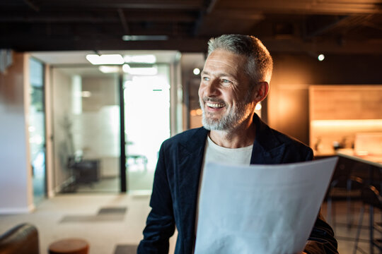 Smiling mature businessman reviewing documents in modern office