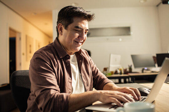 Smiling man working on laptop at home office desk