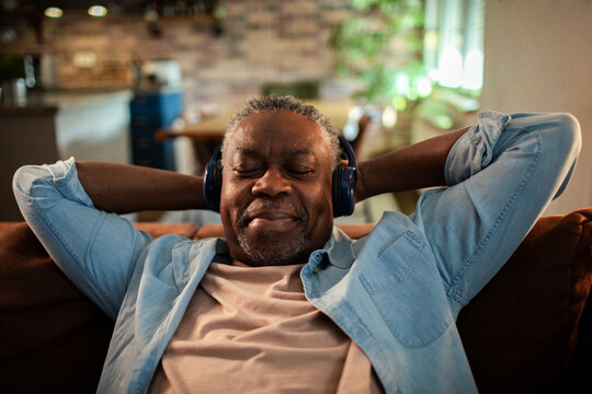 Senior man relaxing with headphones on couch at home