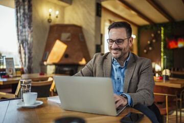 Obraz premium Man working on laptop remotely in cafe
