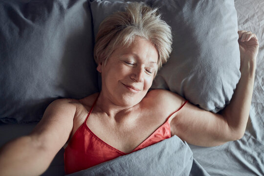 Smiling senior woman relaxing in bed at home