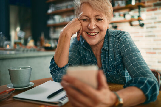 Smiling senior woman using smartphone in cafe