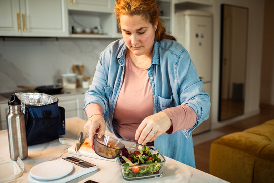 Woman prepping healthy salad in home kitchen