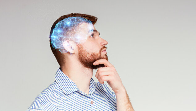 Learning concept. Portrait of thoughtful guy with shining brain on beige background, panorama, copy space