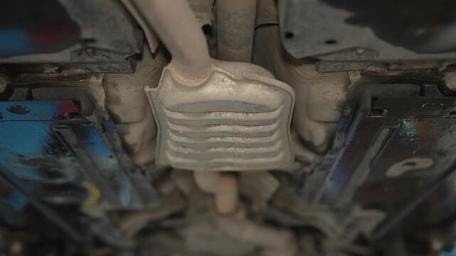 A car exhaust muffler with a chrome tailpipe visible from underneath the rear bumper.