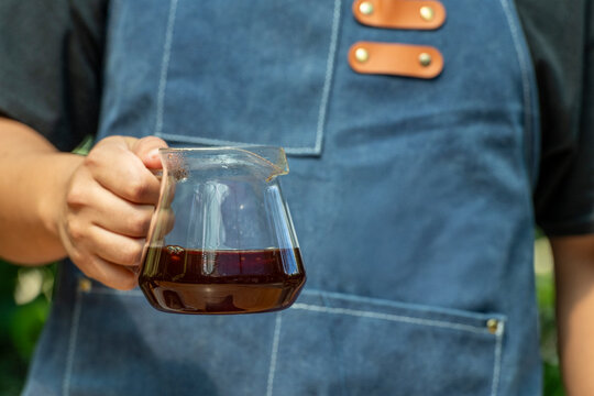 arista holding a glass server filled with freshly brewed Panama Geisha filter coffee, showcasing specialty coffee culture and the art of pour-over brewing - stock photo