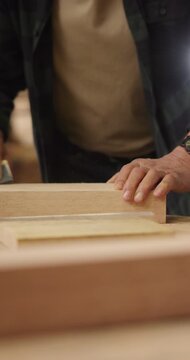 Hands, sandpaper and man smooth wood for carpenter job, woodwork and manufacturing warehouse. Person, productivity and process for texture in workshop with custom or handmade timber furniture