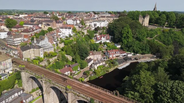 drone view of Knaresborough Viaduct spanning the River Nidd surrounded by lush green trees and traditional architecture.