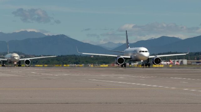 Airplanes Taxiing on the Airport - Sunny Day with Mountains Background