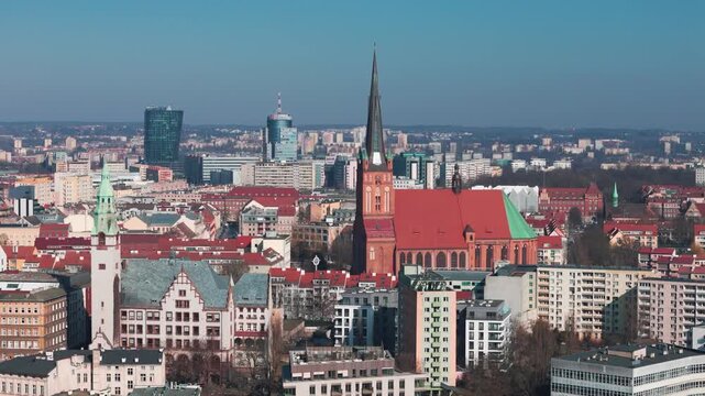 A wide aerial view of the Szczecin city skyline in Poland featuring the Cathedral Basilica of St. James the Apostle, Hanza Tower, and Pazim building under a clear blue sky.