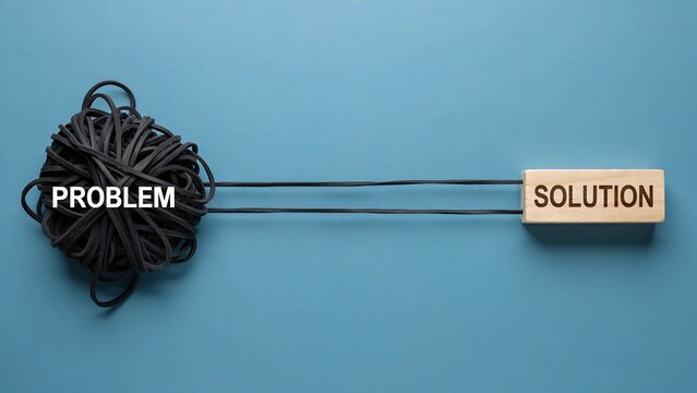 Visual representation of overcoming difficulty using tangled rubber bands as problem linked to wooden block as solution on flat blue surface overhead view conceptual photography.