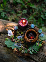 Fototapeta premium witch cauldron, black candle and crystals, acorns, oak leaves in forest, natural background. practical magic, occult ritual, witchcraft, esoteric spiritual ceremony. fairytale, mystery atmosphere