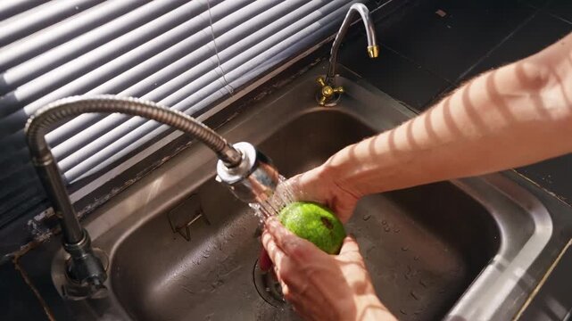 Person Washes Fresh Green Avocado under Running Kitchen Water in Slow Motion, Food Hygiene and Healthy Eating