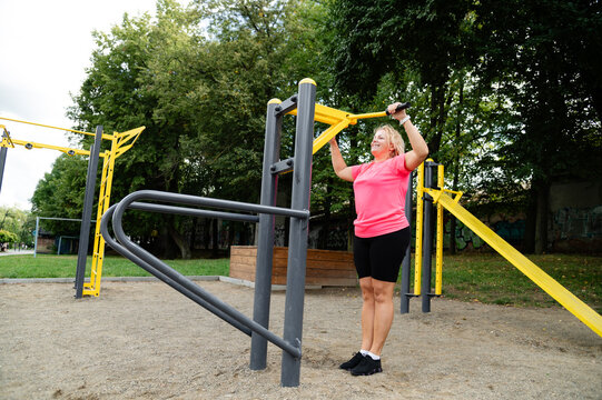 Woman exercises on fitness equipment in public park during daytime