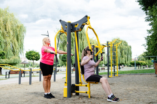 Women exercise together at an outdoor gym in a public park during the day