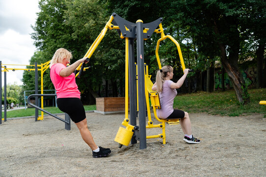 Women exercise together at a public outdoor gym in the park during the day